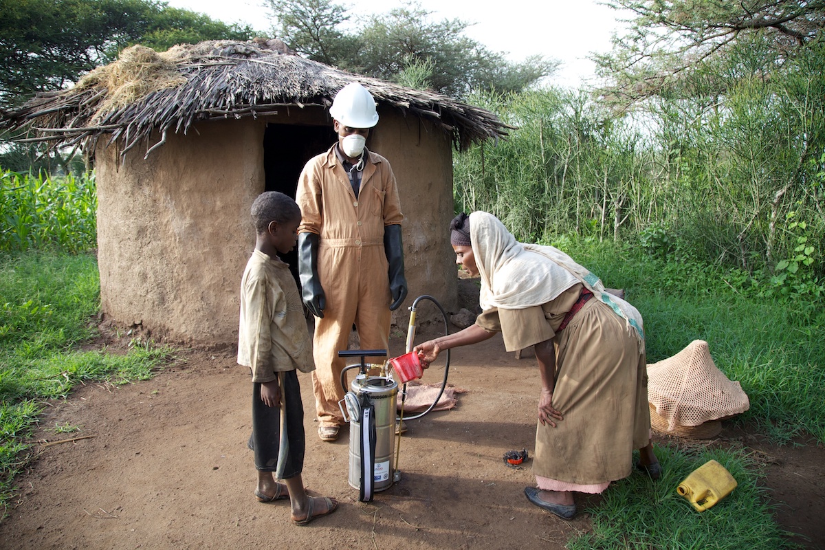 IRS spray operator outside house with family during IRS campaign, Ethiopia, 2014