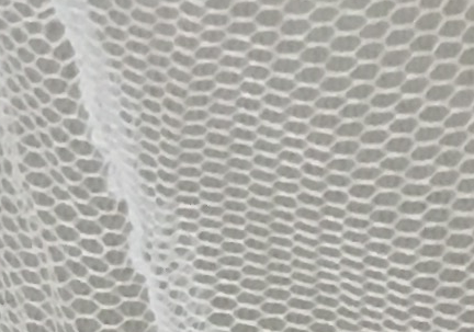 Piece of white mosquito net with dark beige background