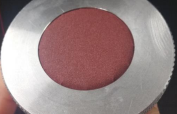 Silver metal circle with red sandpaper at the centre of the circle.