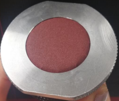 Silver metal circle with red sandpaper at the centre of the circle.