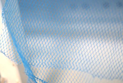 Blue bed net material with beige wall behind